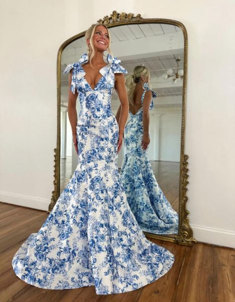 A model in a blue floral print mermaid prom dress with a deep V neckline.