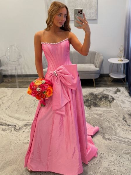 Model confidently posing in the hot pink bow dress against a modern, minimalist backdrop.