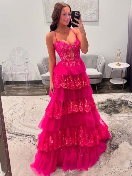 Front view of a vibrant hot pink prom dress with a front lace-up detail, layered skirt, and applique.