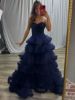 Front view of a navy blue strapless ball gown with layered lace and a full skirt.
