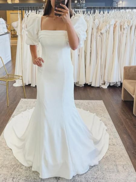 Front view of an ivory satin mermaid wedding dress with romantic puff sleeves.