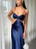 Front view of a navy blue satin prom dress with spaghetti straps, a bow accent, and cutout details.