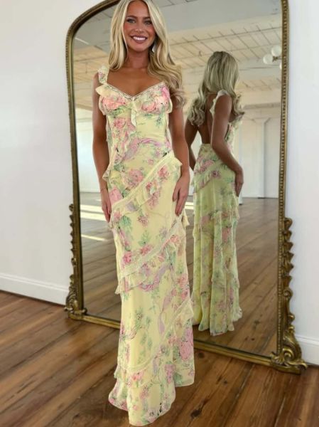 Front view of a sunny yellow maxi prom dress covered in a floral print with cascading ruffles.