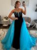 Front view of a strapless prom dress in black and blue with intricate beading.