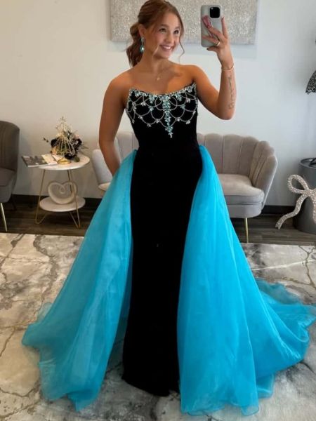 Front view of a strapless prom dress in black and blue with intricate beading, worn with a detached overskirt.