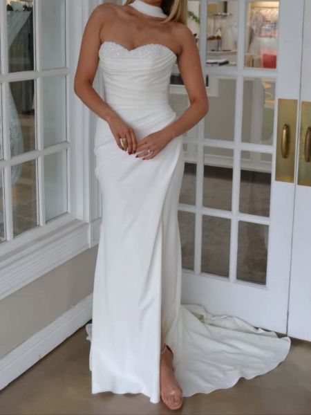 Front view of a satin mermaid wedding dress with a detailed hand-beaded strapless bodice.