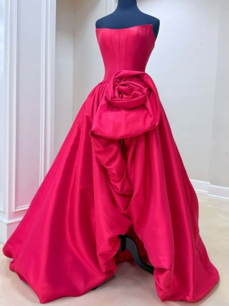 Front view of a simple strapless prom gown in satin, featuring a sculptural 3D rose detail.