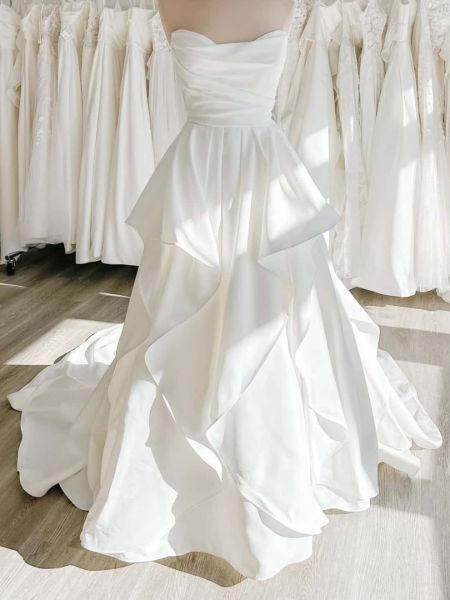 Front view of a white strapless wedding dress with a tiered A-line skirt.