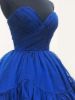 Close-up of the ruched detailing and draping on the bodice of the blue dress.