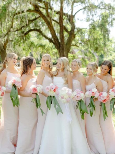 Blush pink satin bridesmaid dress with thin spaghetti straps and a fitted mermaid silhouette.