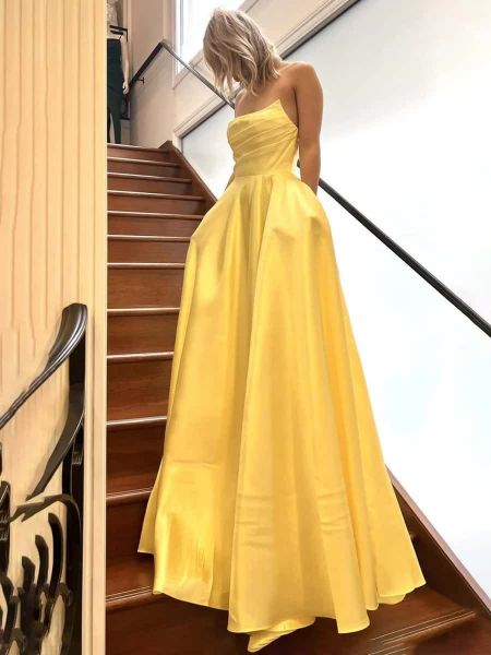 Elegant strapless yellow ball gown with a full, voluminous skirt and hidden pockets.