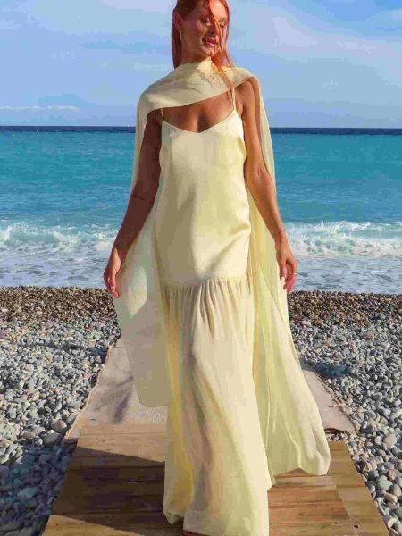 Pale yellow spaghetti strap maxi dress with flowing attached cape and soft, ethereal fabric.