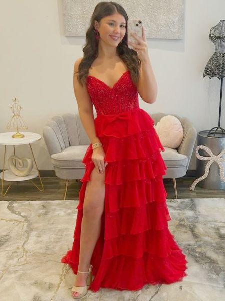 Red rhinestone prom dress with corset bodice, cascading ruffles, and dramatic thigh-high slit.