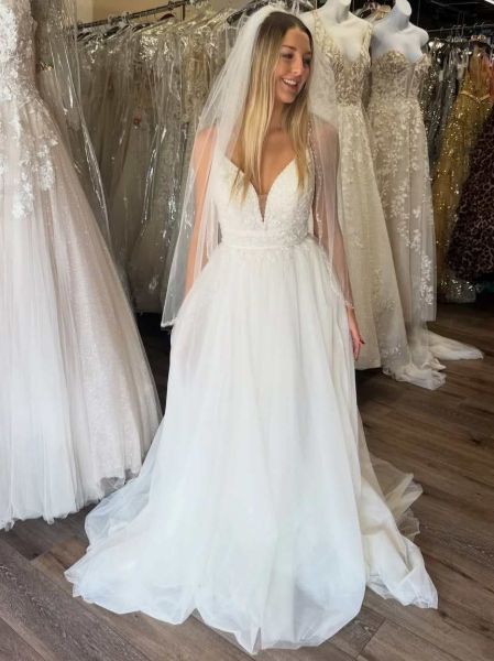 White lace V-neck A-line bridal dress with matching veil, delicate lace appliqués, and flowing skirt.