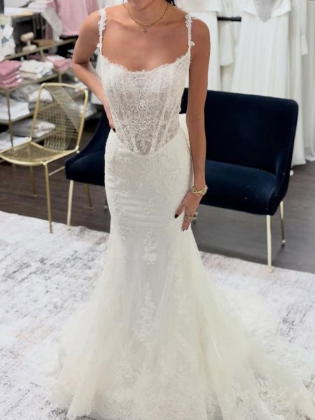 Modern sheer bodice mermaid wedding dress with delicate lace appliqués floating on illusion fabric and dramatic train.